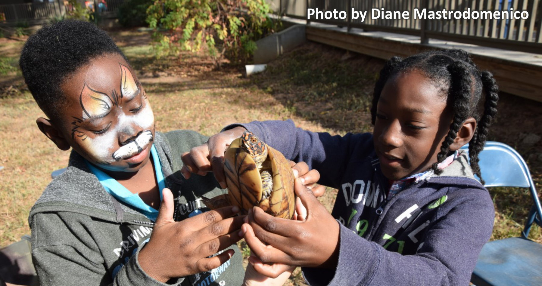 Two children at an outreach event holding a box turtle together. Photo by Diane Mastrodomenico.
