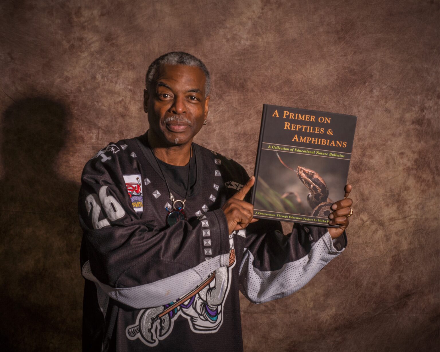 LeVar Burton holding a copy of A Primer on Reptiles & Amphibians.